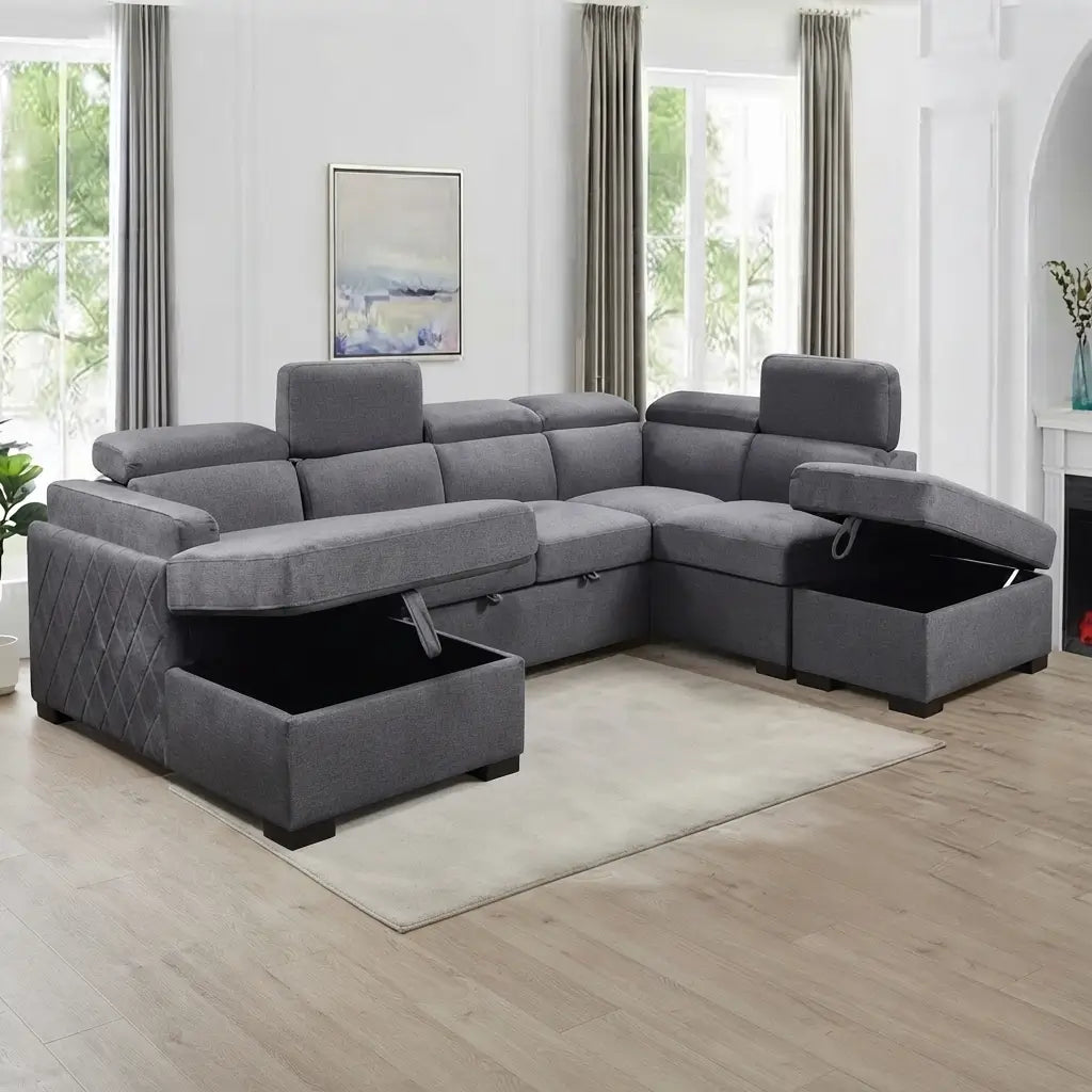 A gray fabric sectional sofa with storage compartments underneath the front ottomans, shown in a bright, modern living room setting with light wood floors and large windows.