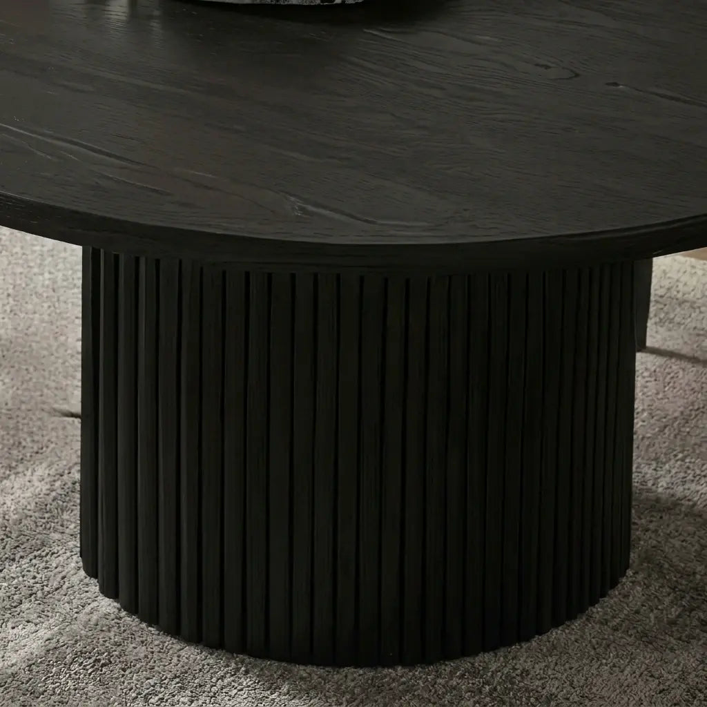 Modern fluted pedestal dining table with black oval top.