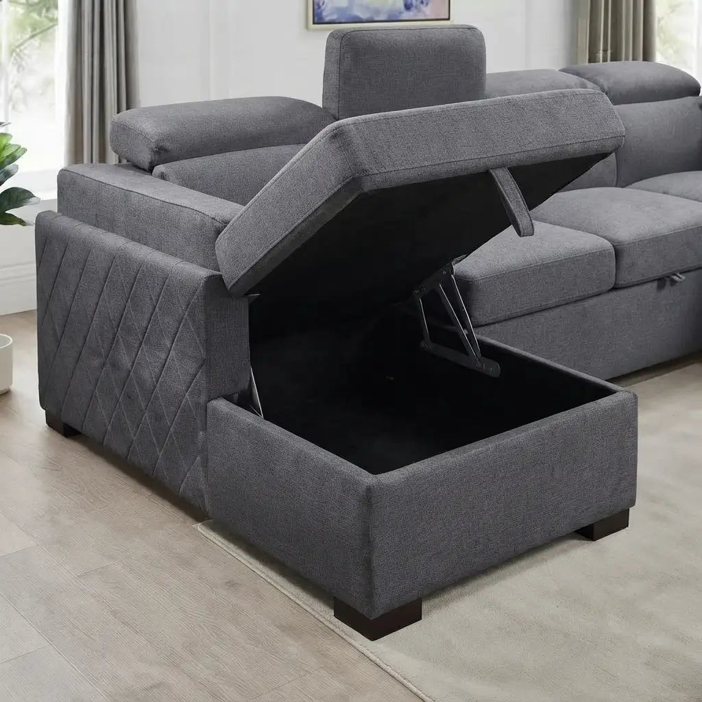 A gray upholstered storage ottoman or lift sofa shown in a real living room, with the front storage compartment open and the seat cushion raised by a lift mechanism.
