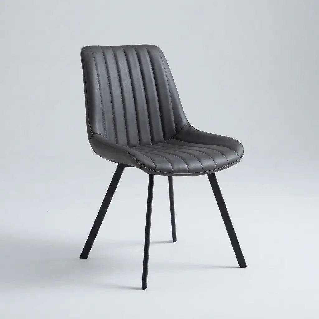 A modern dining chair with a dark gray ribbed faux leather upholstered seat and backrest, supported by four slim black metal legs, shown against a light gray studio background.