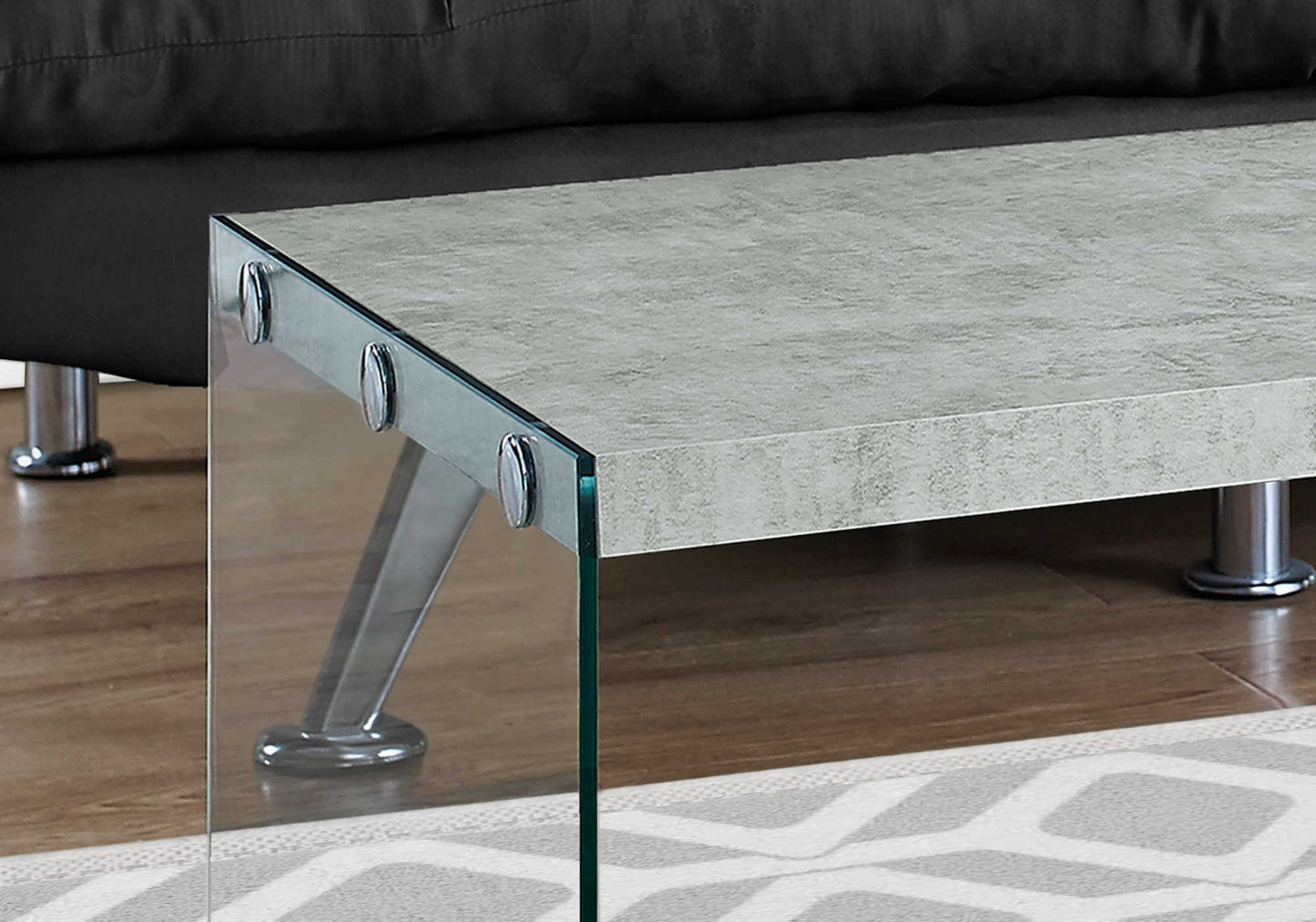Close-up of high-quality cement-look top and sturdy tempered glass legs on this modern coffee table