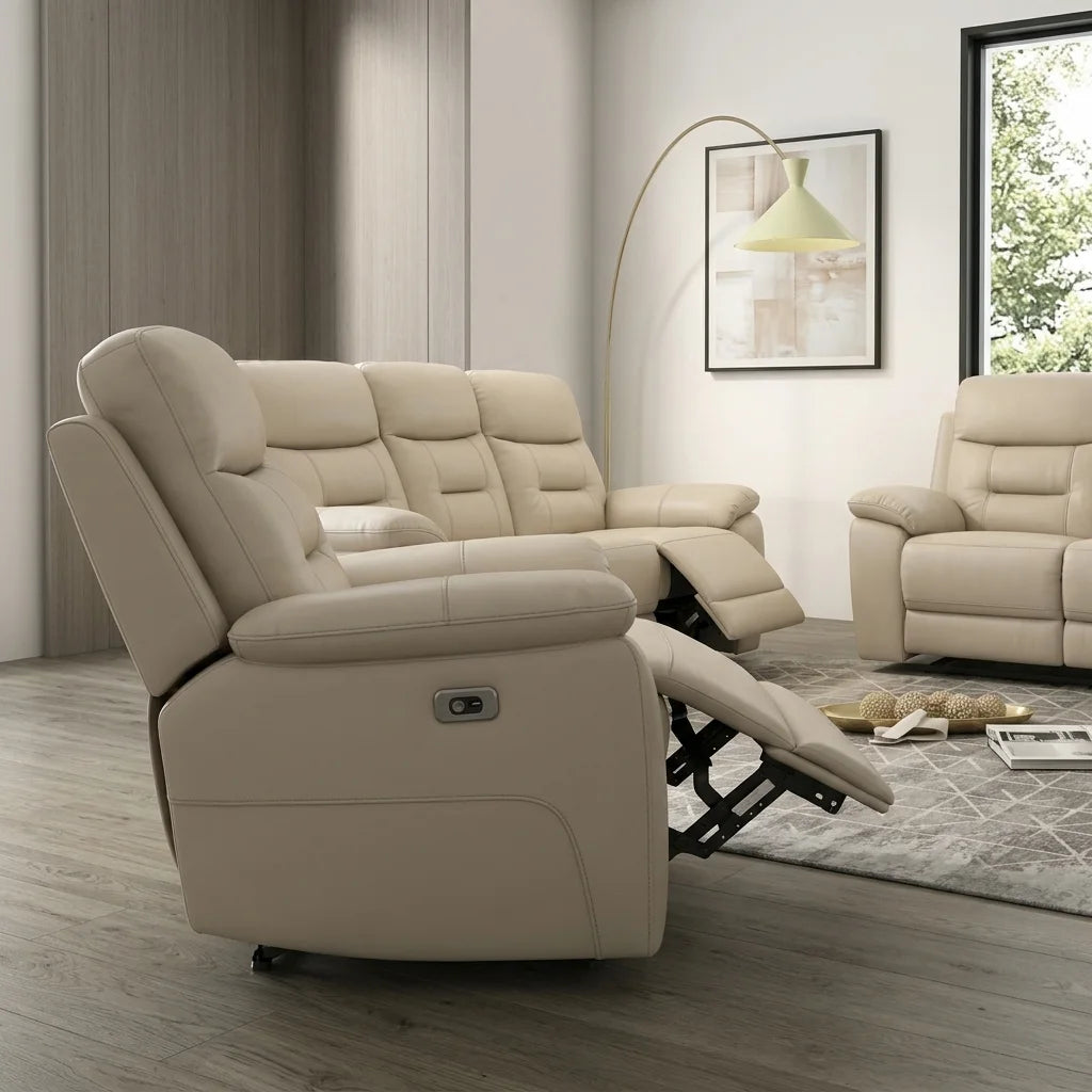 A photorealistic image showing the rear view of a light beige leather power-reclining sofa. The perspective highlights the smooth leather back panels and the visible dark metal mechanism under the extended footrest. The sofa sits on light wood floors in a modern room with framed art and another leather sofa partially visible.