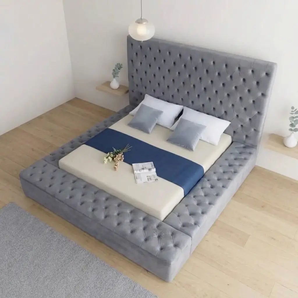 Luxury grey velvet upholstered bed with deep button tufting on the rectangular headboard and platform perimeter, shown with bedding