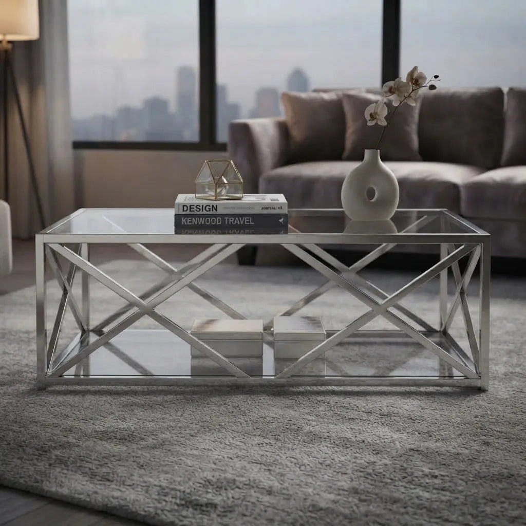 Contemporary coffee table with a thick clear tempered glass top and polished silver chrome X-style metal base, offering a sleek and elegant centerpiece.