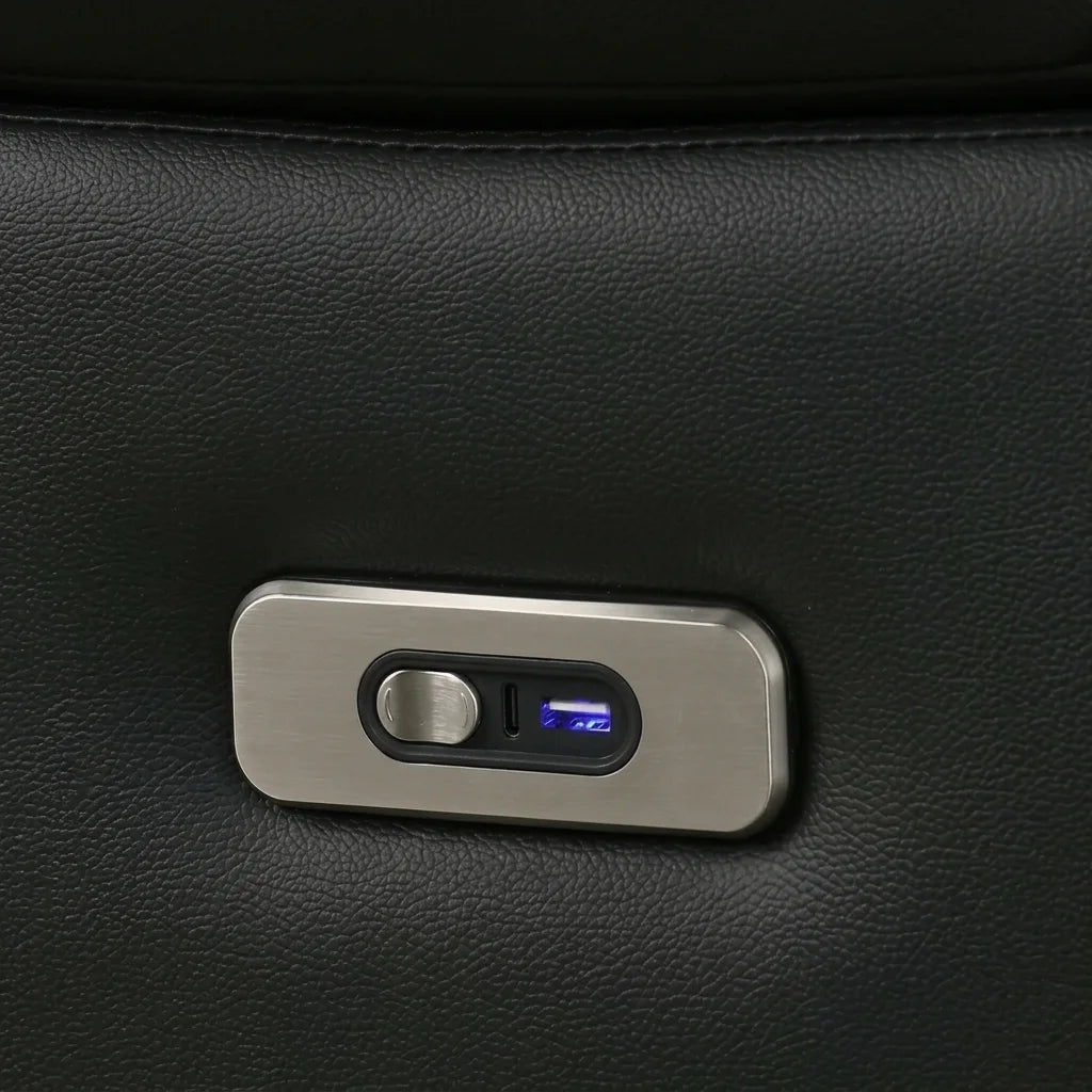 Close up detail of a power recliner's metallic control switch with an integrated USB charging port on a black leather surface.